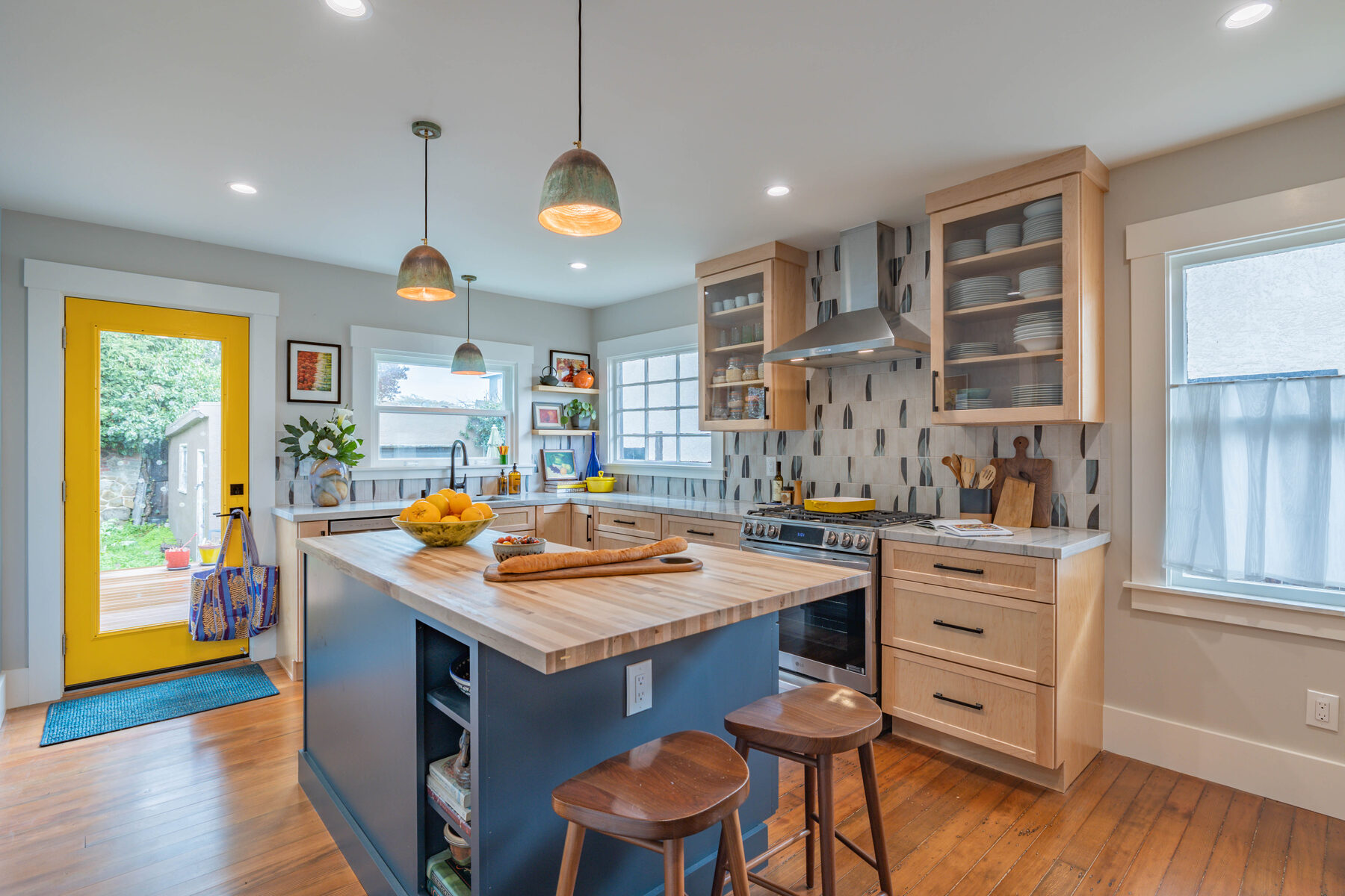 Wide kitchen view with yellow door and blue island