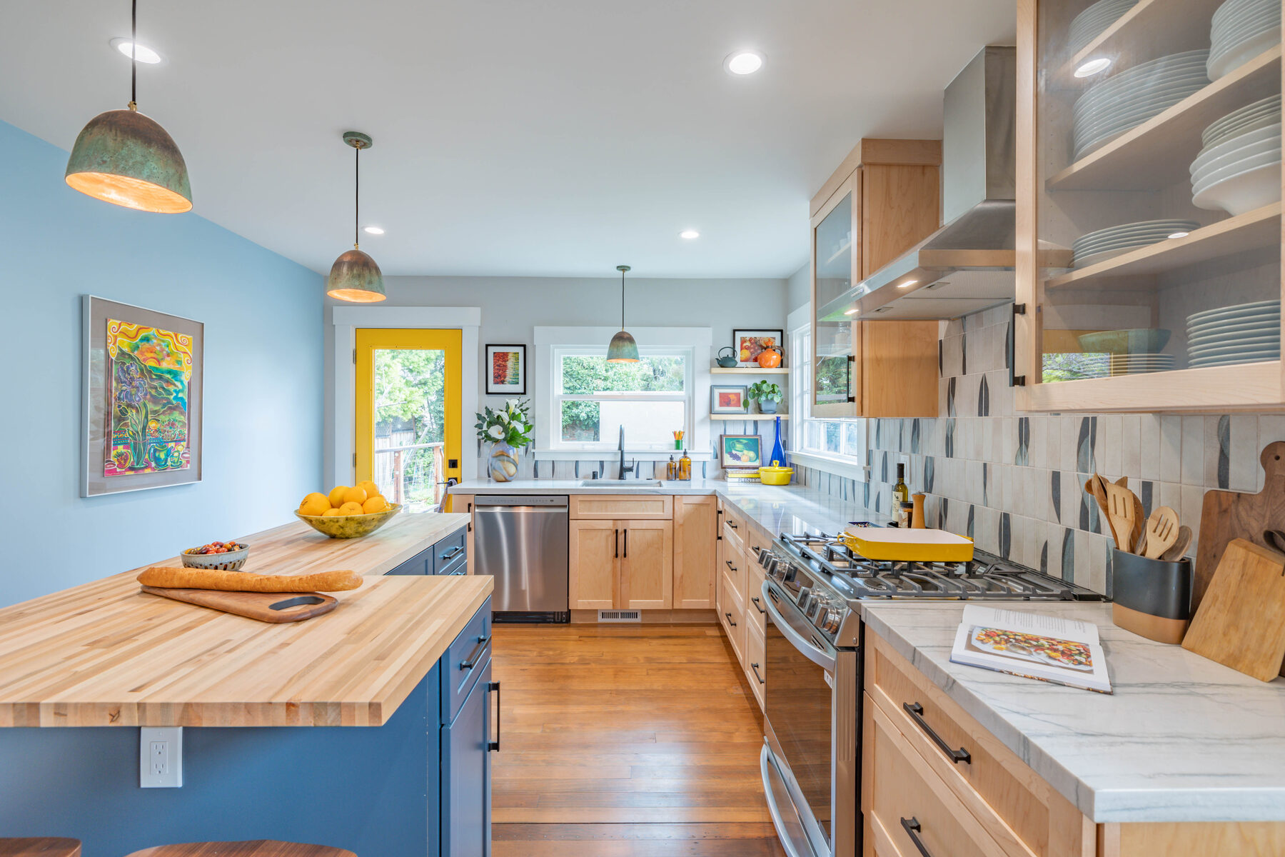 Counter view with marble, blue cabinets, and pendants beyond