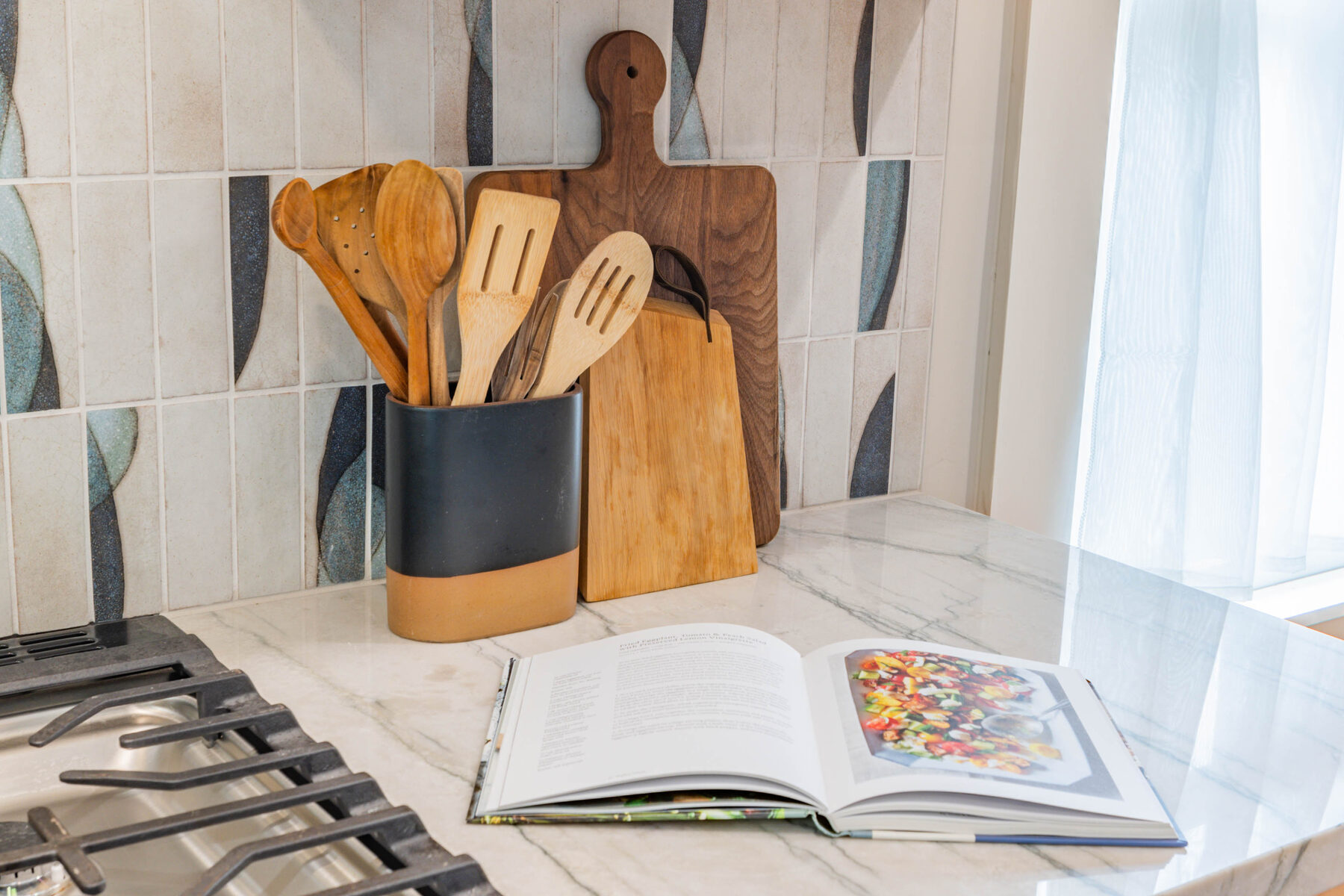 Wooden utensils on marble counter with custom tile