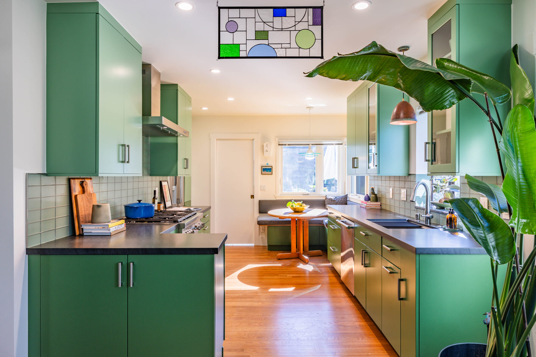 Kitchen galley view with stained glass panel and two-tone green cabinetry