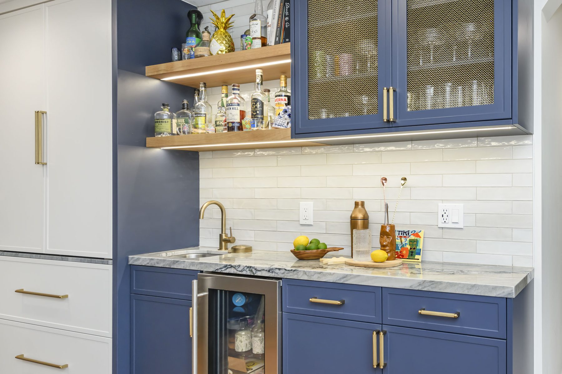 Navy bar nook with brass mesh cabinets and floating white oak shelves