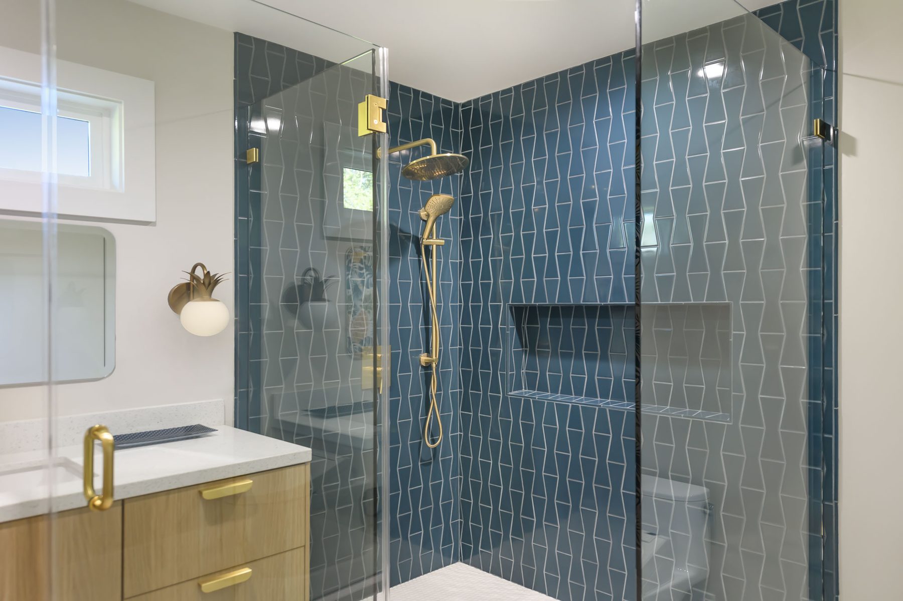 Guest shower with deep teal elongated diamond glass tile, brass rainhead and handheld, and brass pineapple sconce