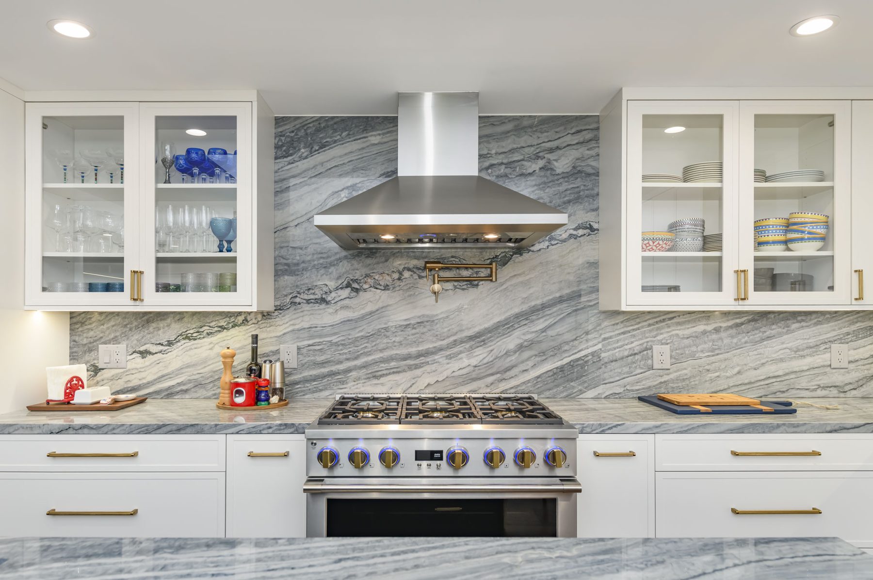 48-inch pro range with brass-collared knobs against book-matched quartzite range wall