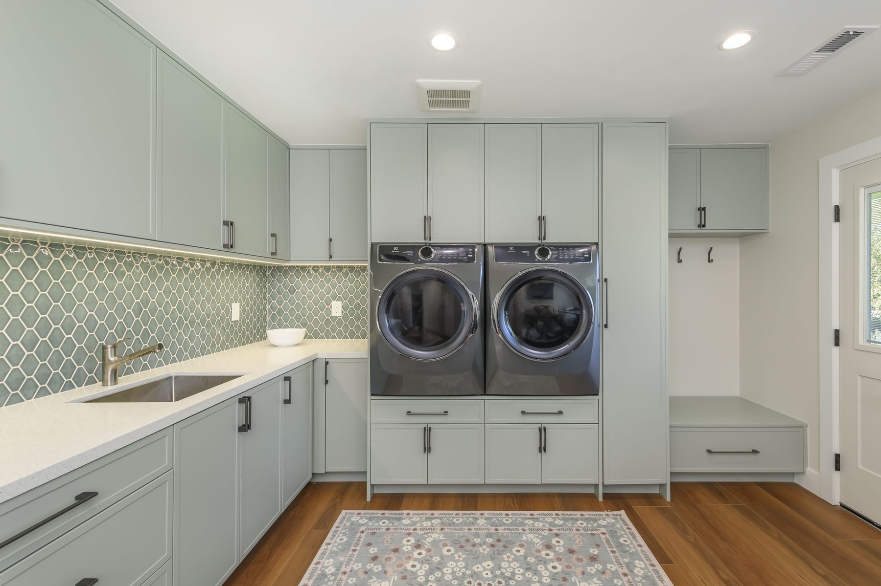 Sage green laundry room with elongated honeycomb mosaic backsplash