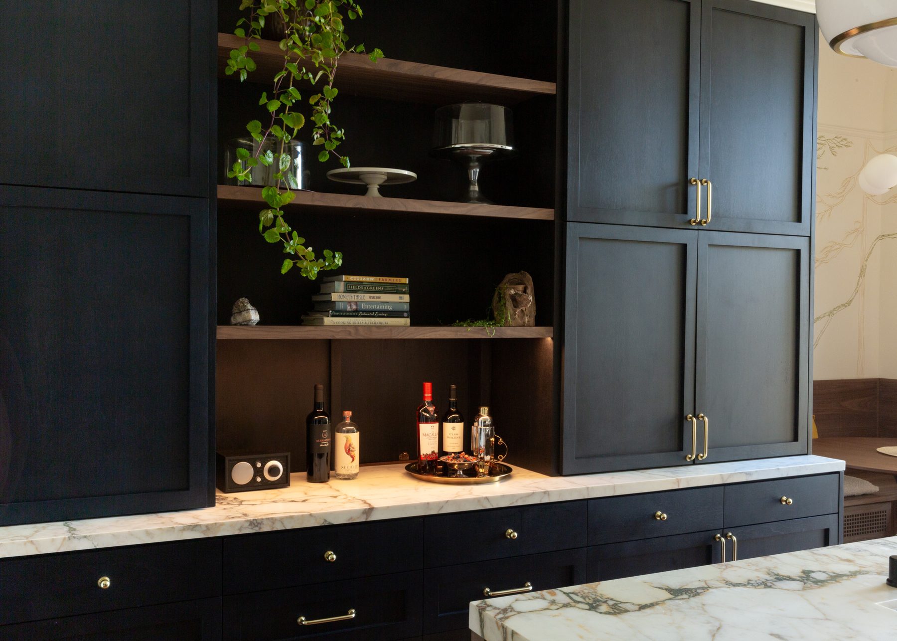 Open bar shelving with books, plants, and glassware beside navy cabinetry