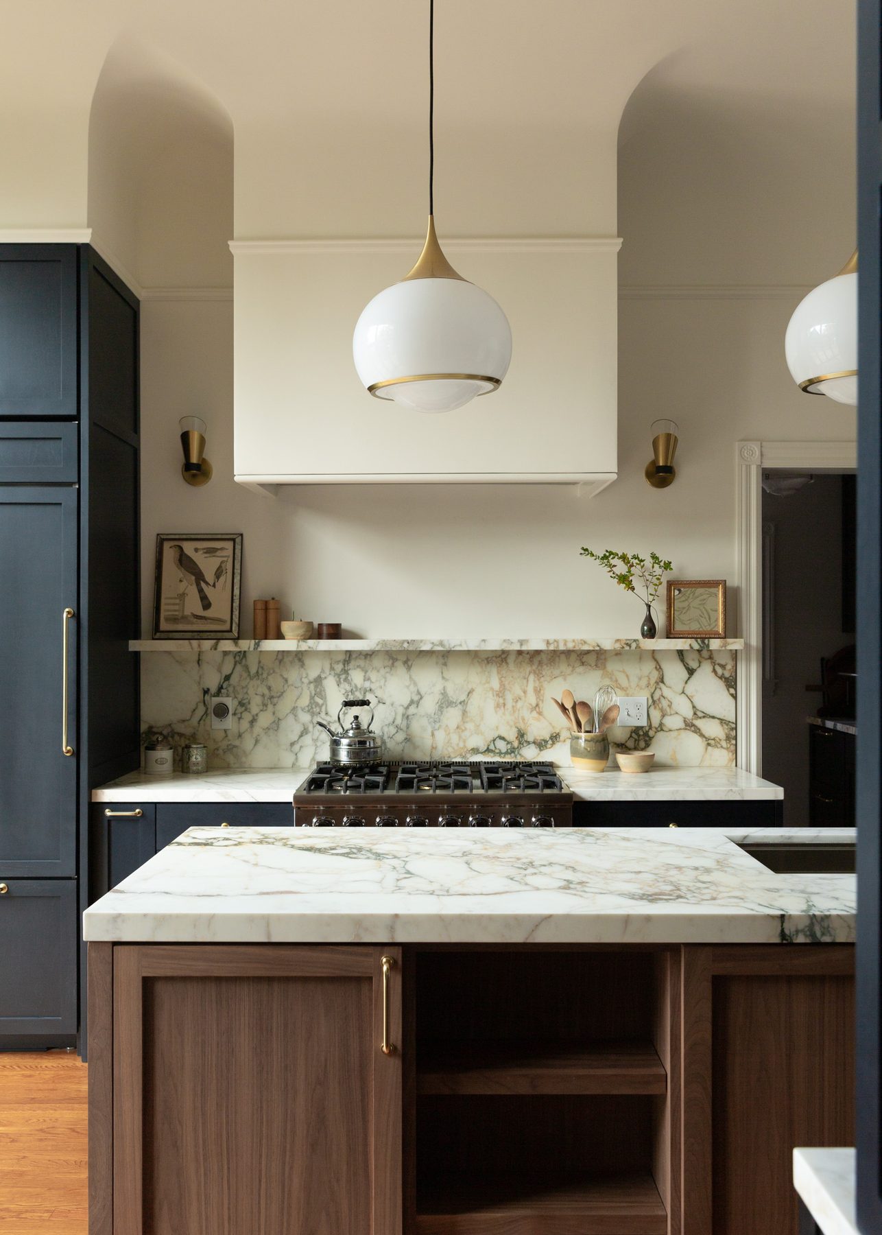 Range wall with hand-veined marble backsplash seen past the walnut island