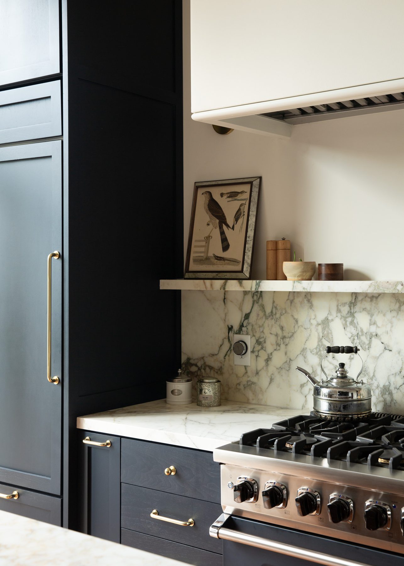 Close view of the range shelf styled with a framed bird print and kettle