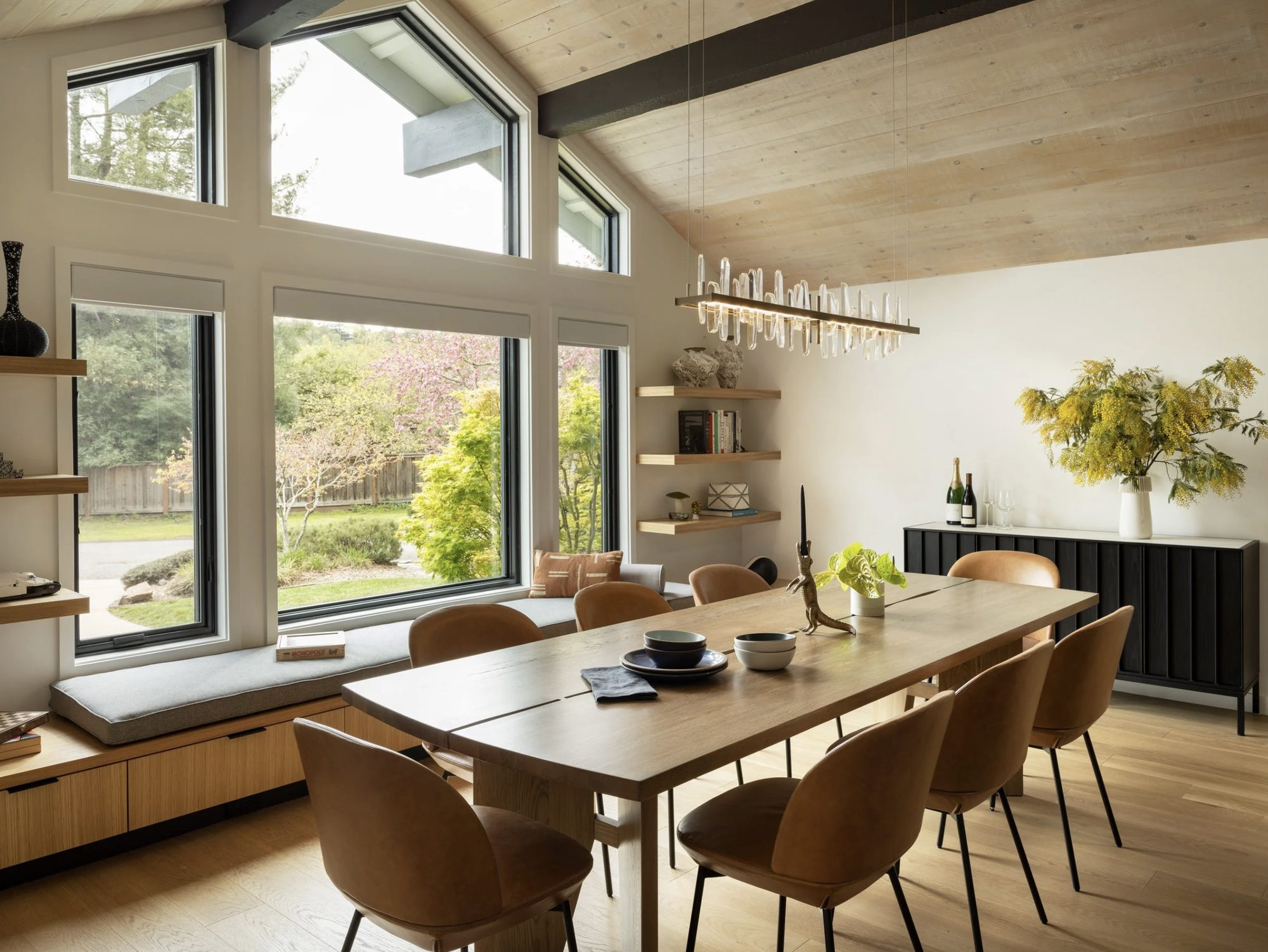 Dining room beneath a vaulted wood ceiling and gable windows