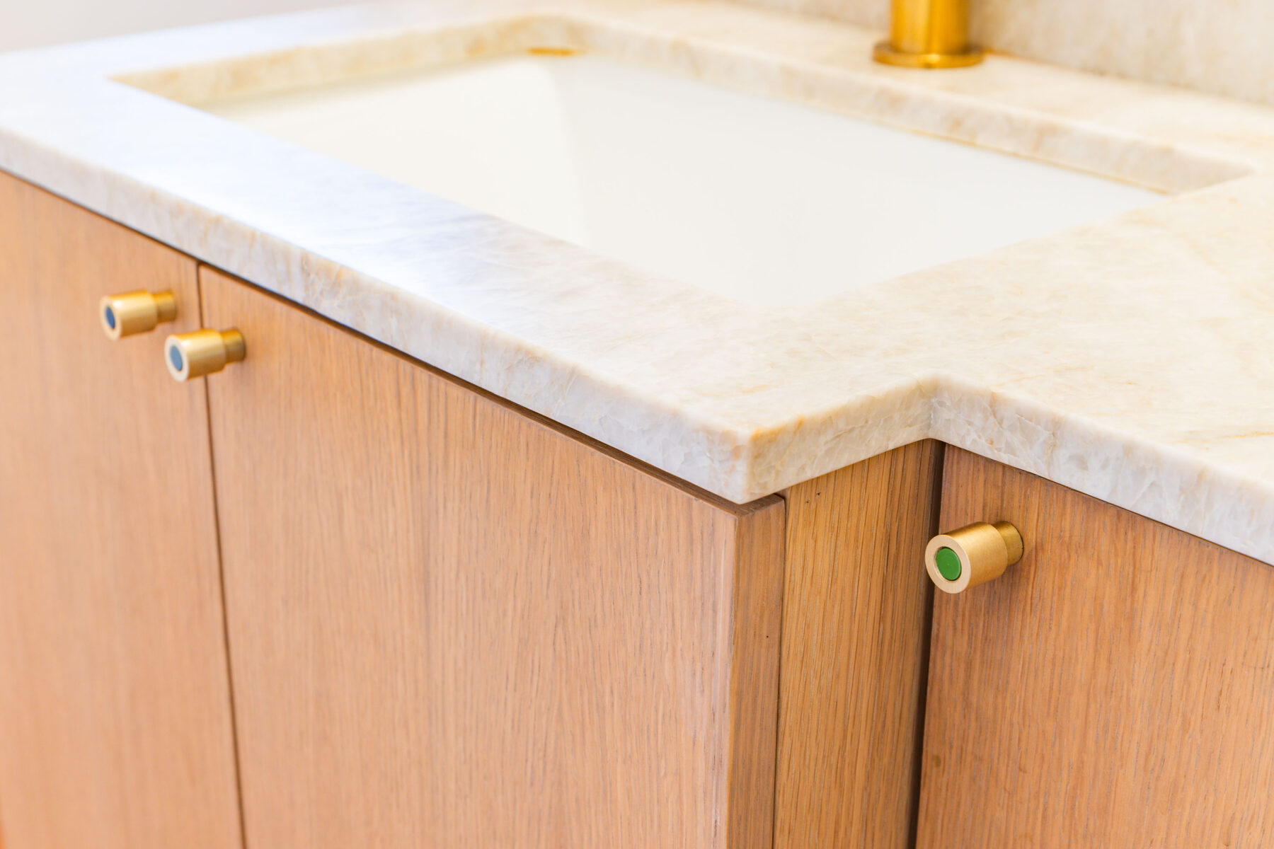 Quartzite vanity edge detail with custom brass and ceramic knobs