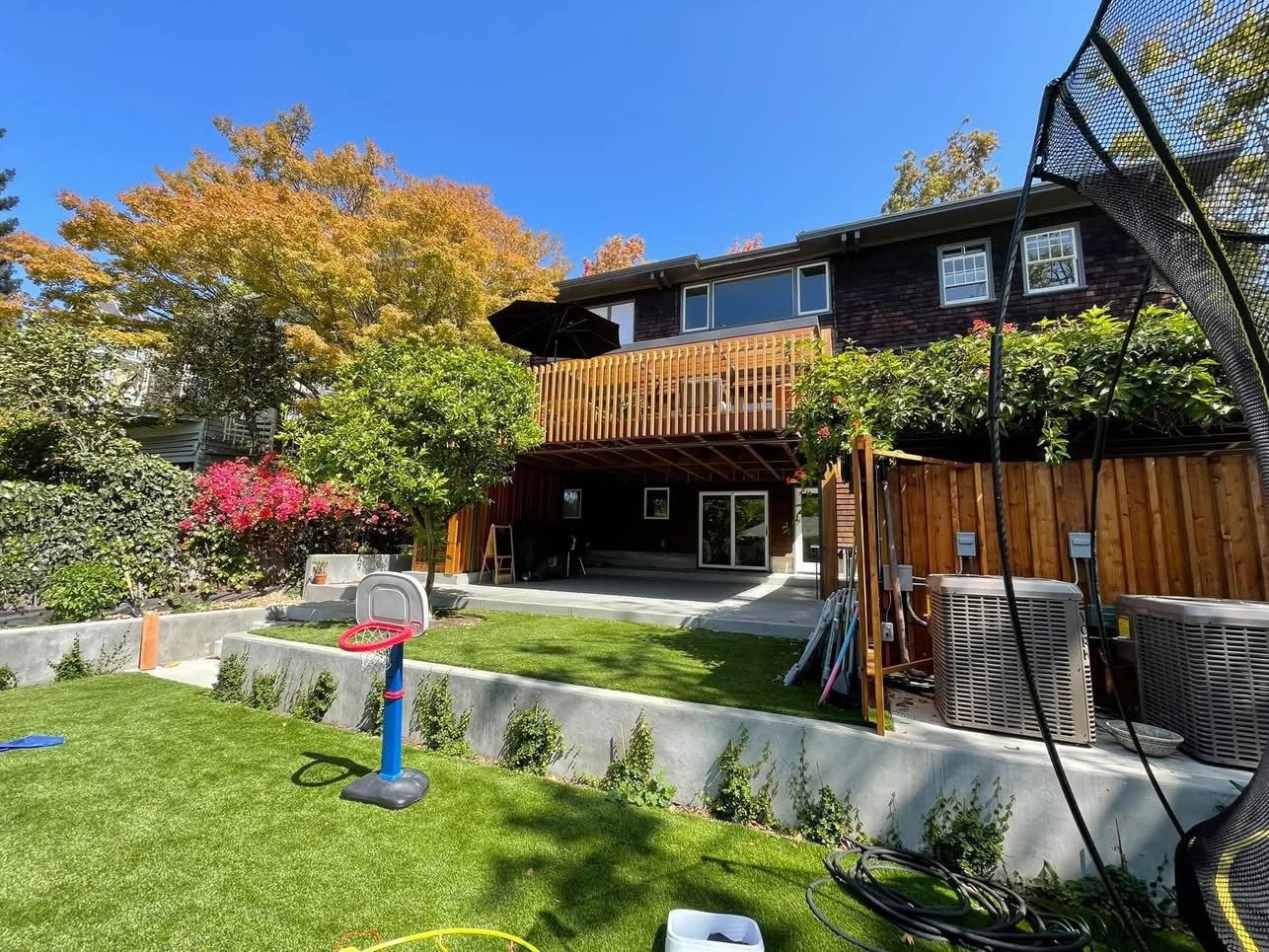 Full backyard view showing the elevated deck above a covered patio and level lawn